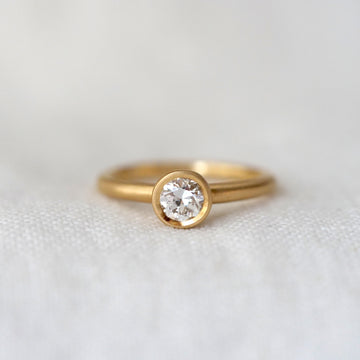 Gold ring with a diamond on a light gray background