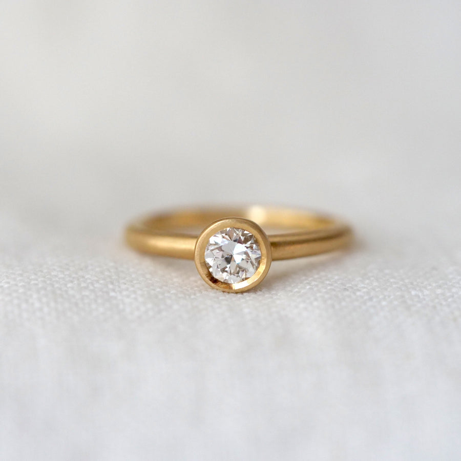 Gold ring with a diamond on a light gray background
