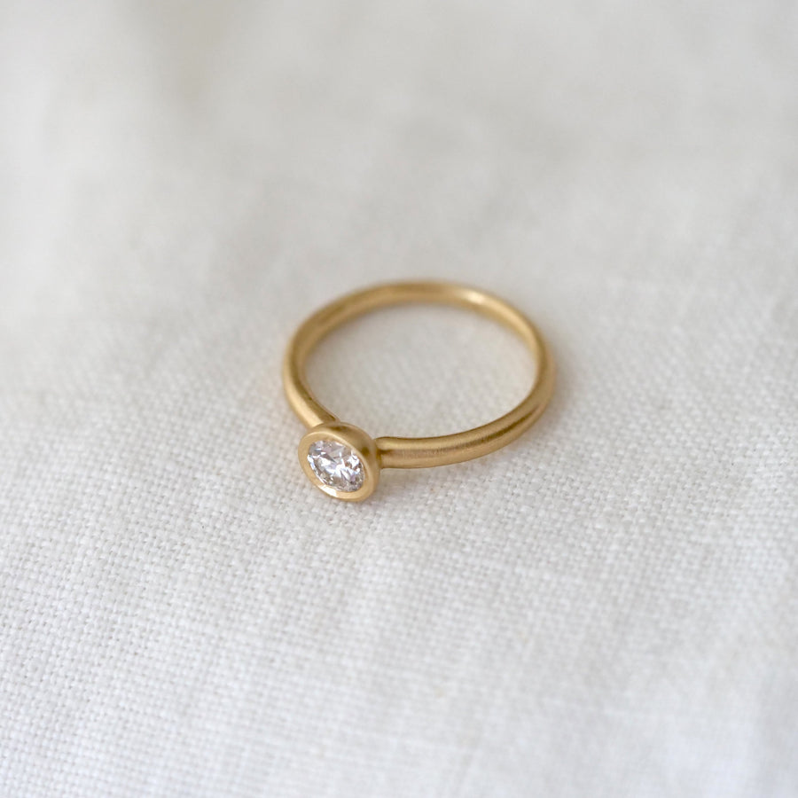 Gold ring with a diamond on a white fabric background