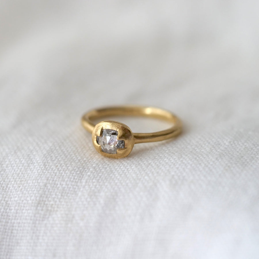 Gold ring with a diamond on a white fabric background