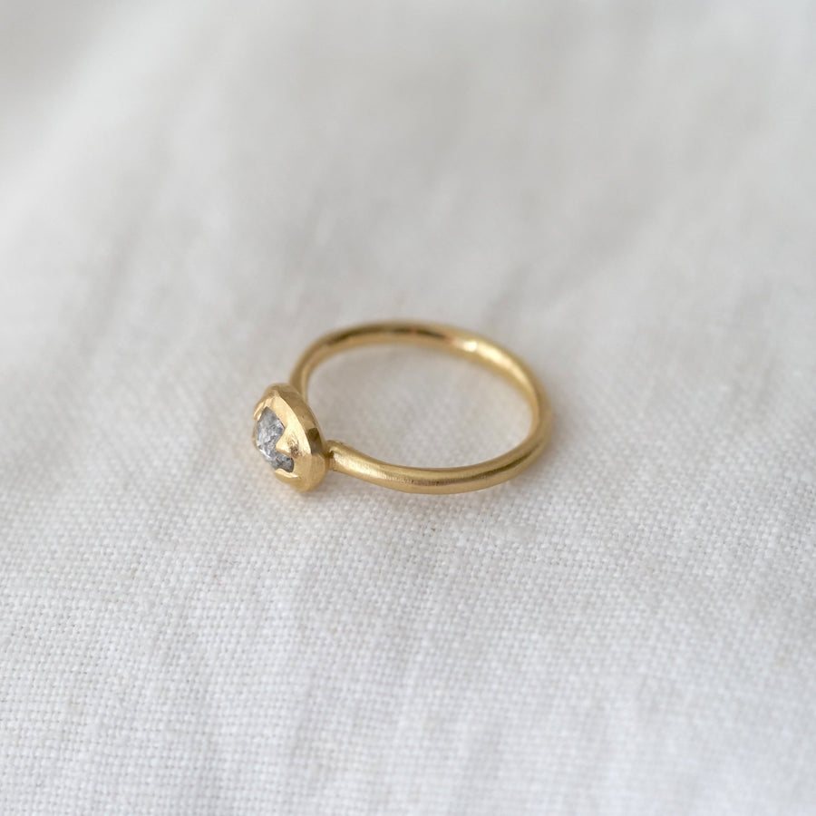 Gold ring with a small gemstone on a white fabric background