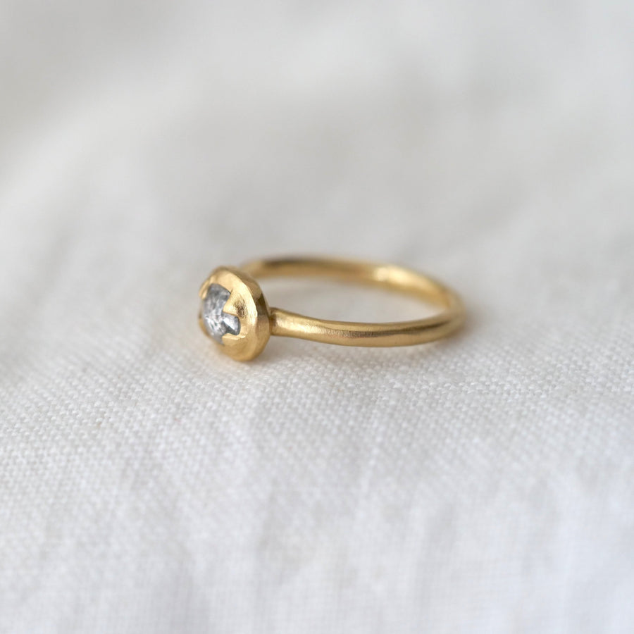 Gold ring with a small diamond on a white fabric background