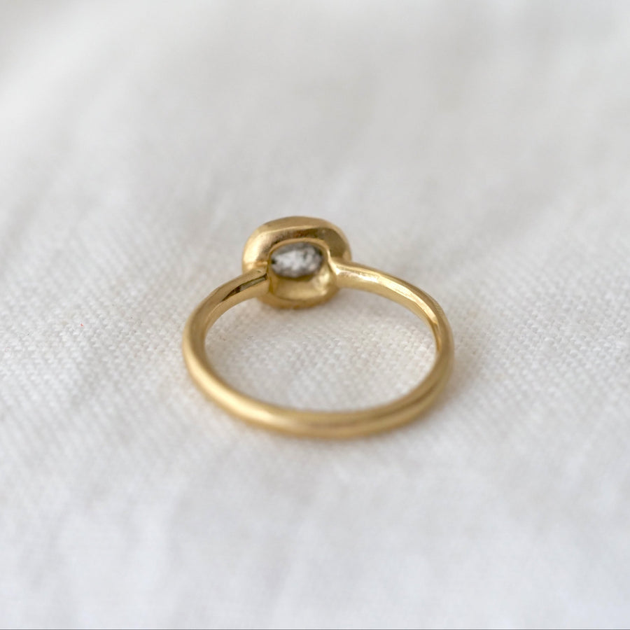 Gold ring with a small diamond on a white fabric background