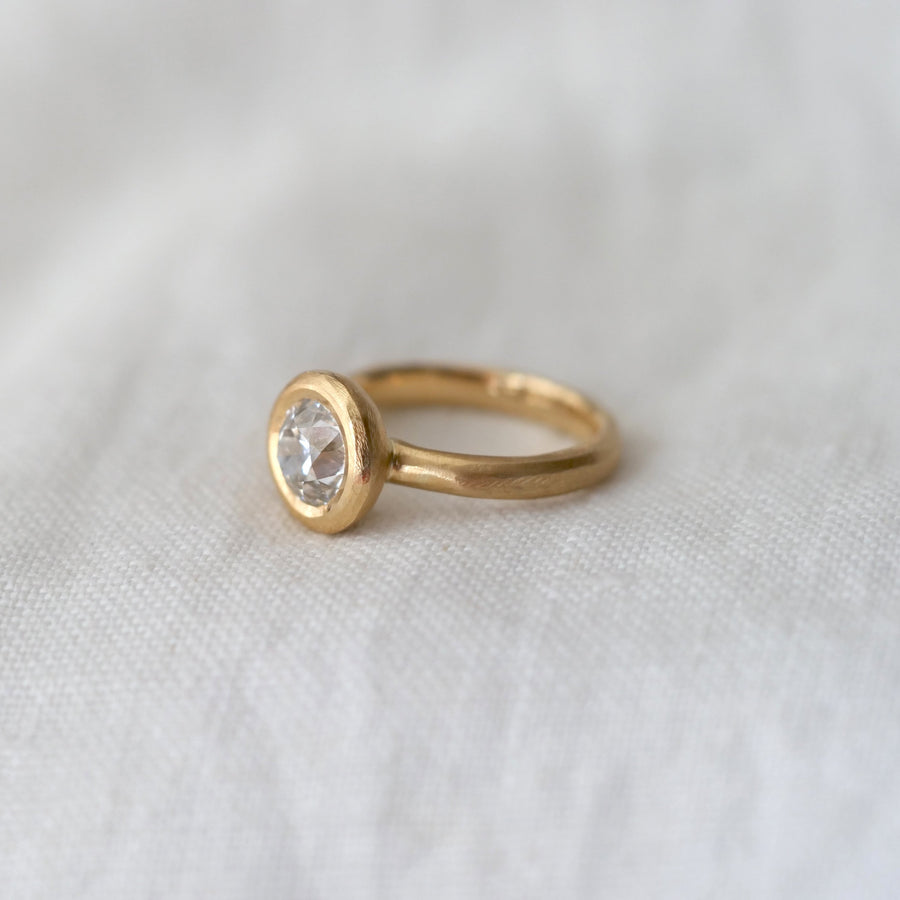Gold ring with a diamond on a white fabric background