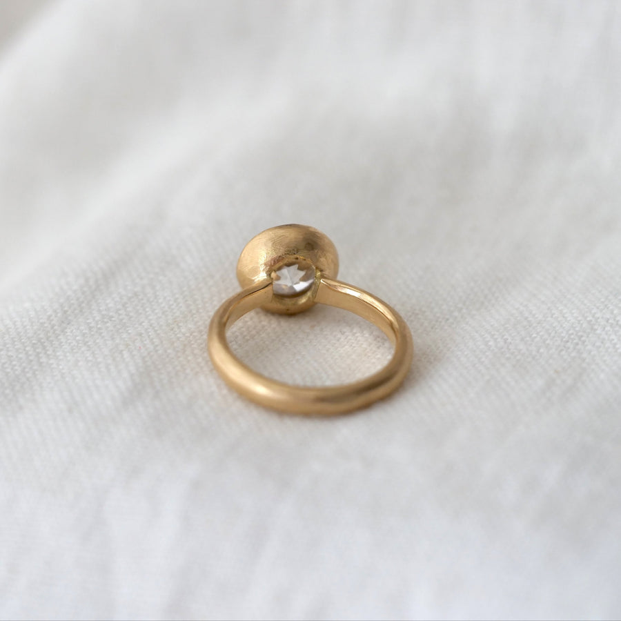 Gold ring with a diamond on a white fabric background