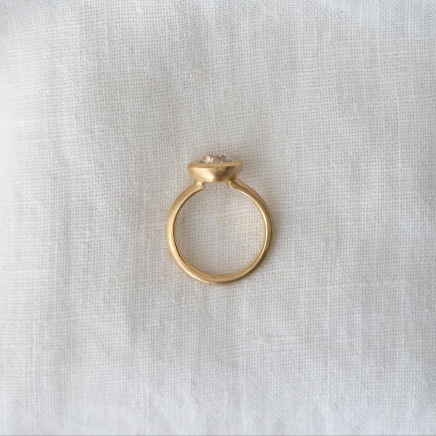 Gold ring with a diamond on a white fabric background