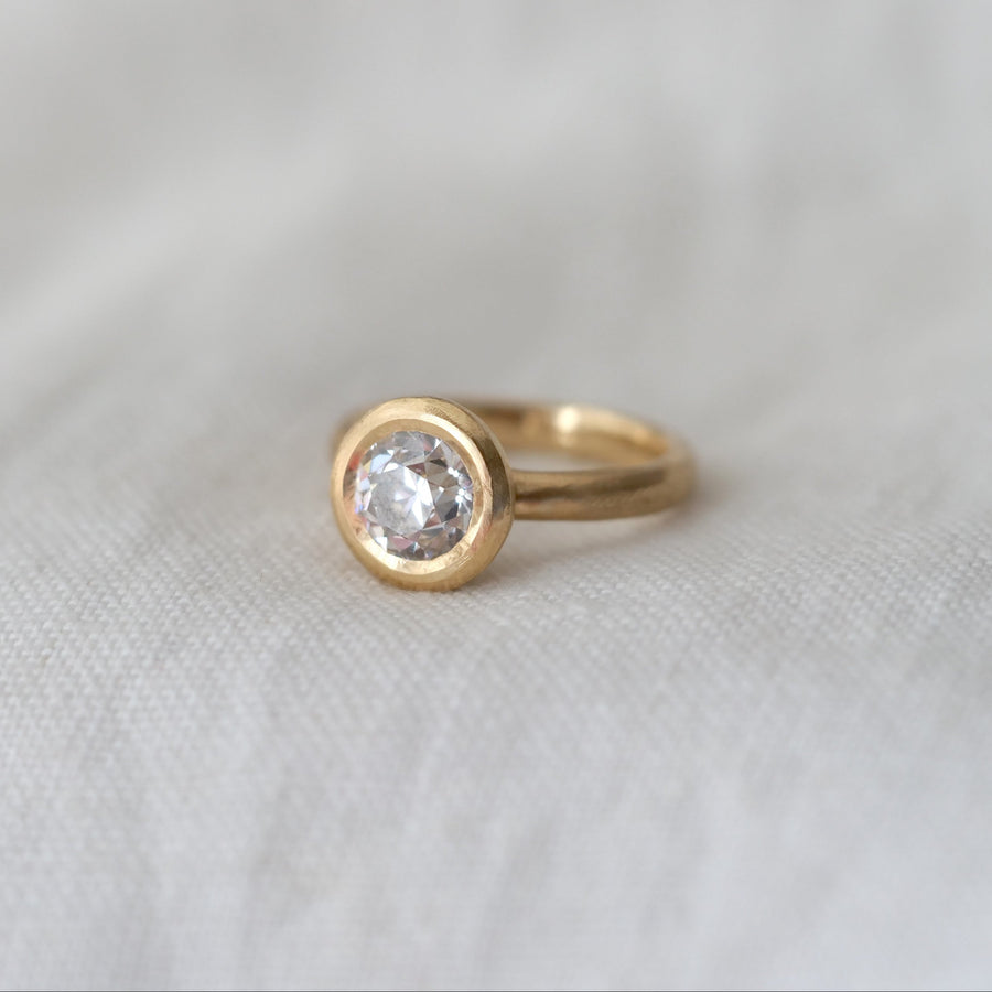 Gold ring with a diamond on a white fabric background