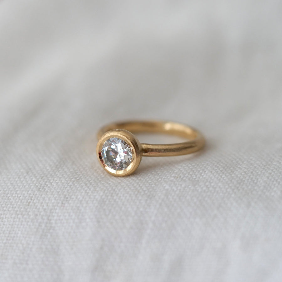 Gold ring with a diamond on a white fabric background