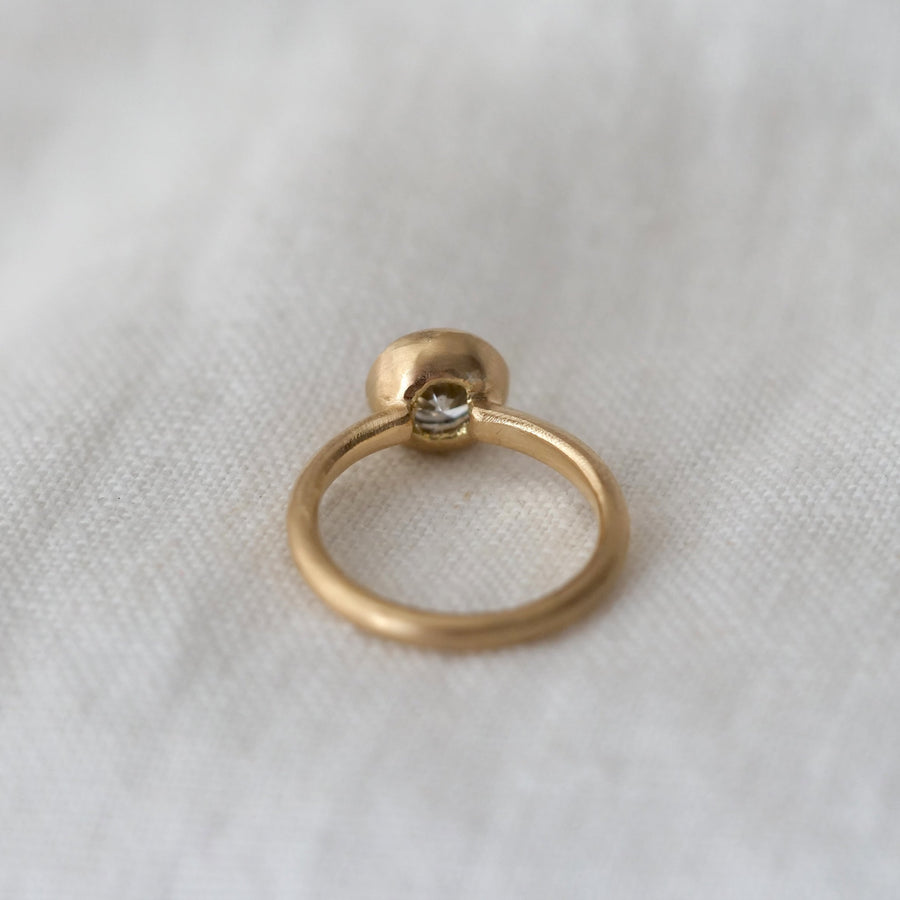 Gold ring with a diamond on a white fabric background