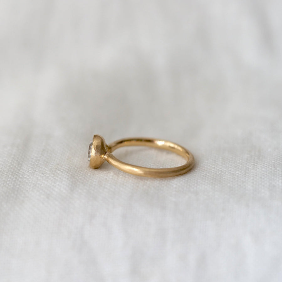 Gold ring with a diamond on a white fabric background