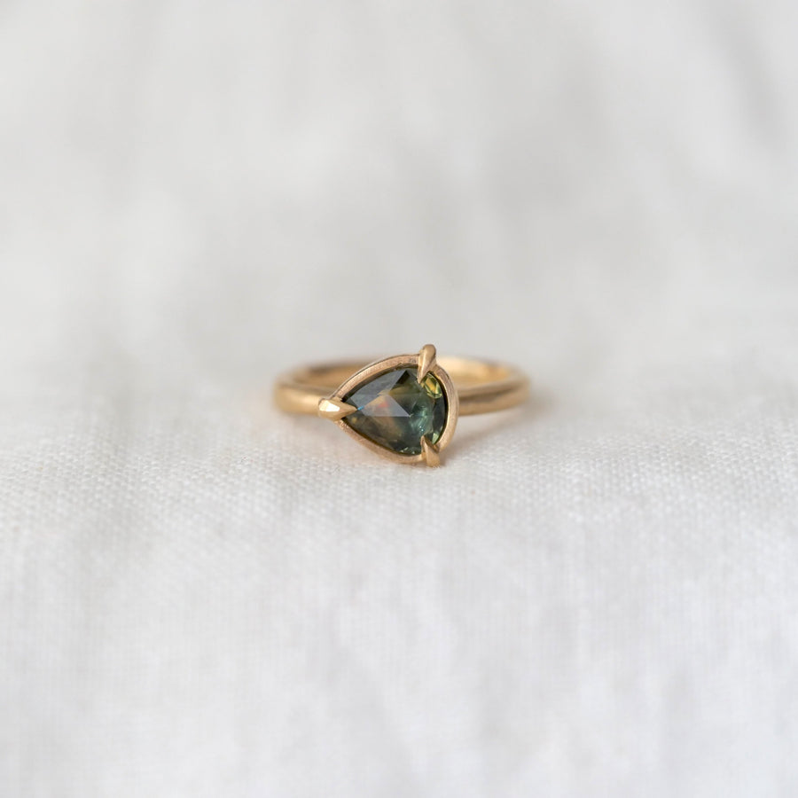 Gold ring with a green gemstone on a white background