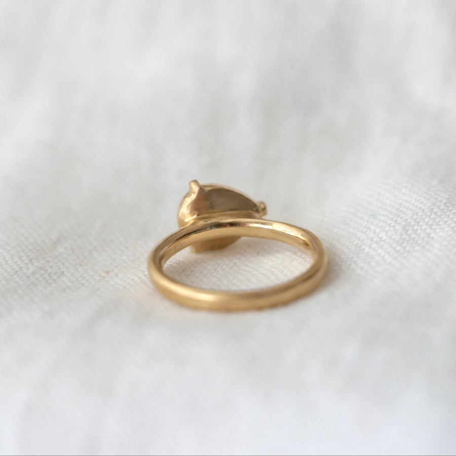 Gold ring with a heart-shaped design on a white fabric background