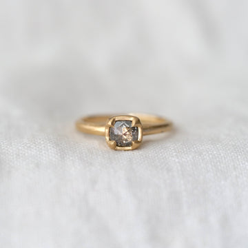 Gold ring with a gray rose cut diamond four prong set in gold, on a white fabric background