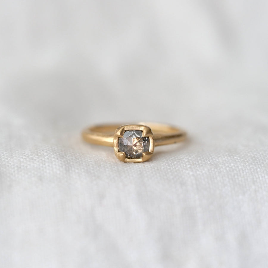 Gold ring with a gray rose cut diamond four prong set in gold, on a white fabric background