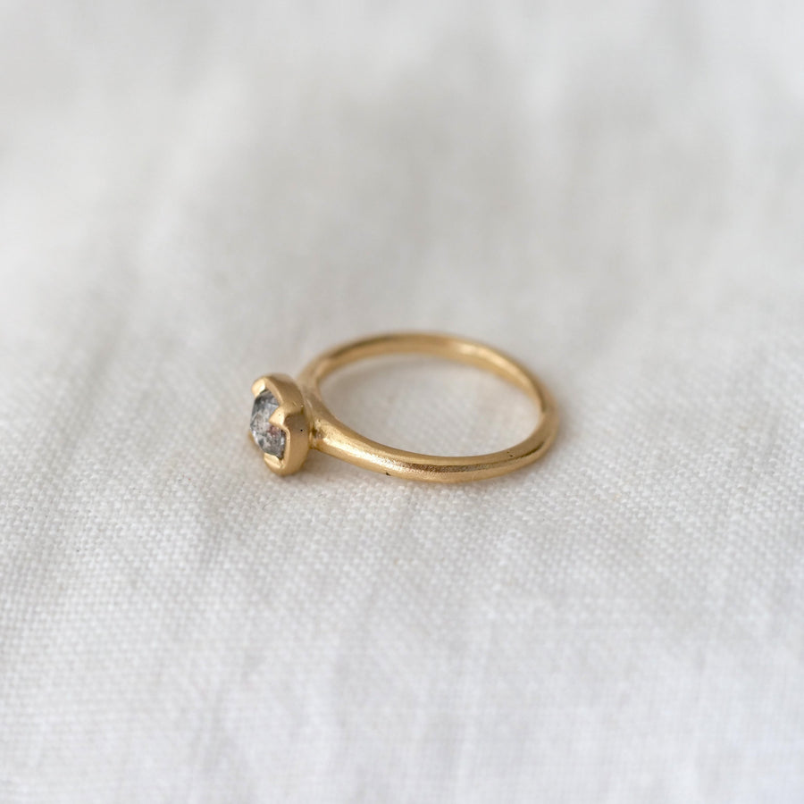 Gold ring with a diamond on a white fabric background