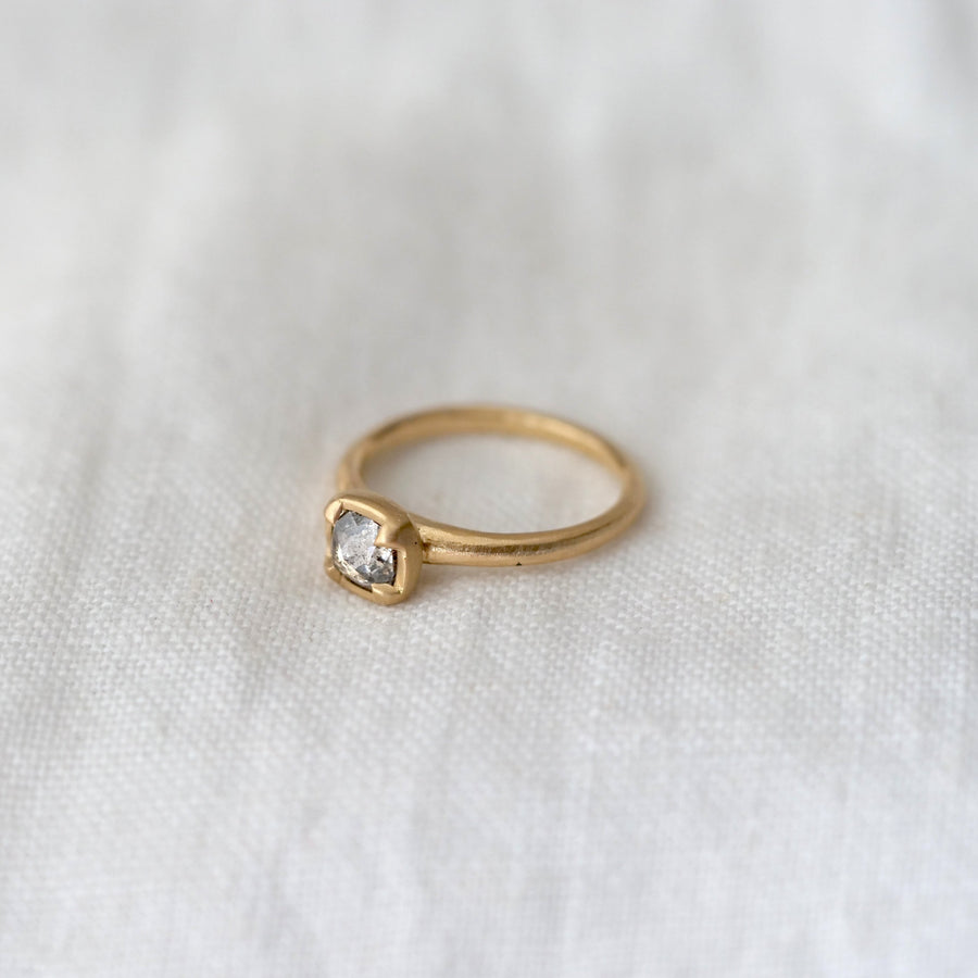 Gold ring with a diamond on a white fabric background