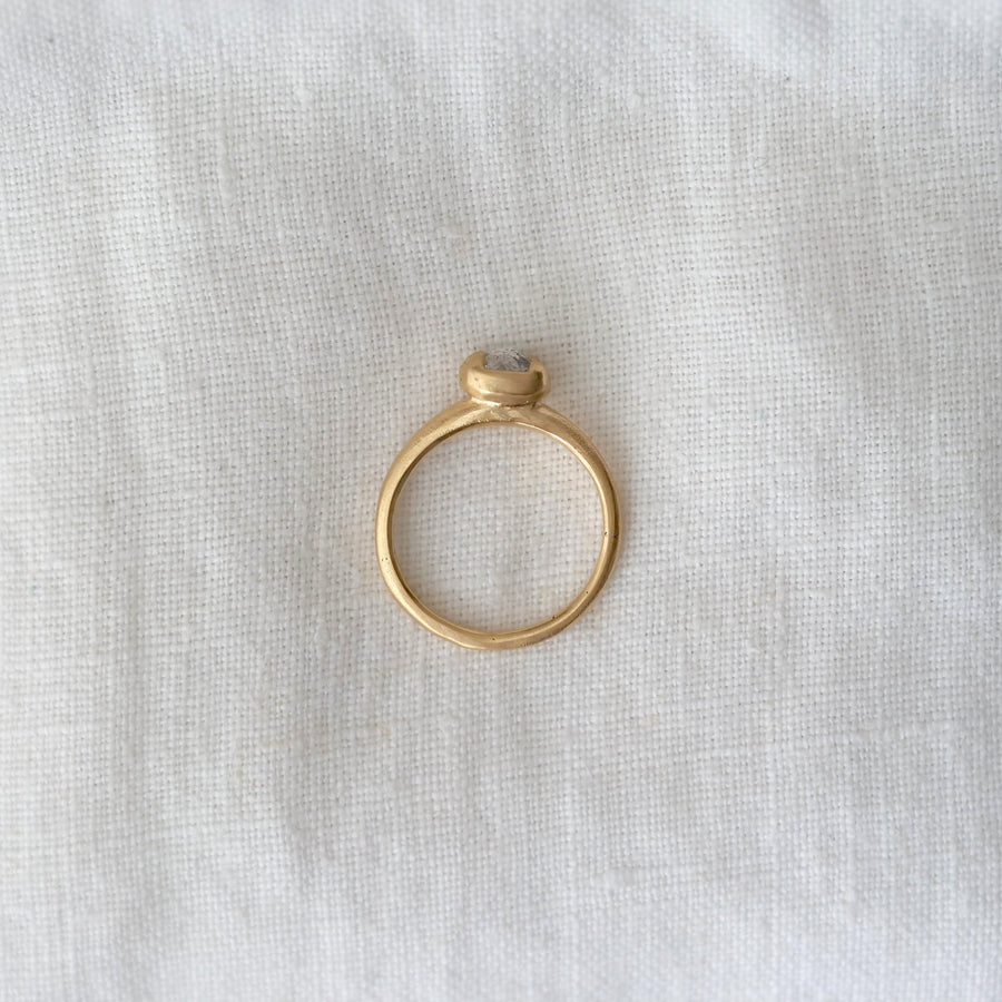 Gold ring with a small stone on a white fabric background