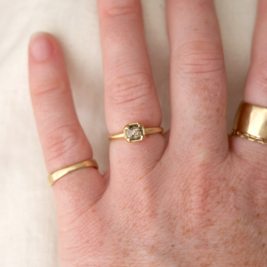 Hand wearing two gold rings on a plain background