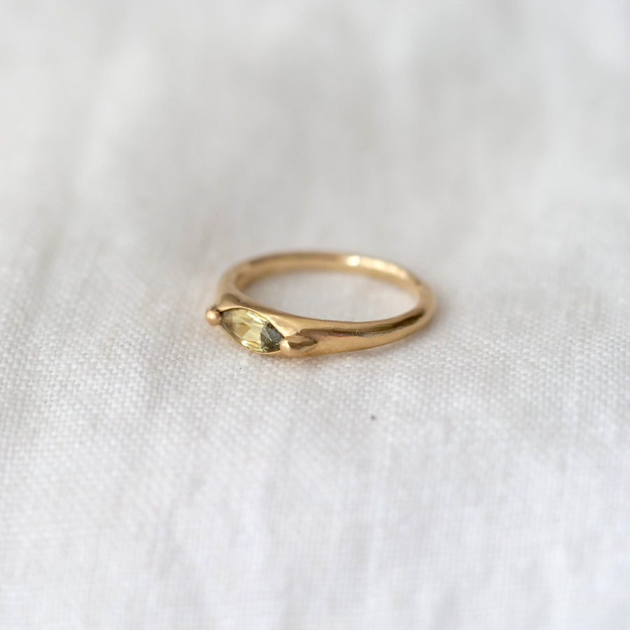 Gold ring with a green stone on a white fabric background
