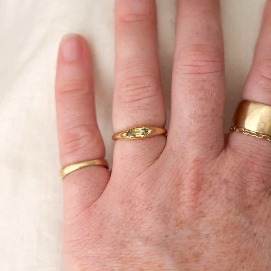 Hand wearing three gold rings on a plain background
