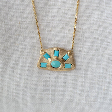arched Gold necklace with turquoise stones on a light gray background