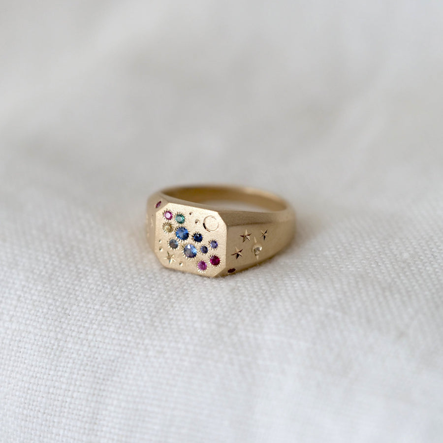 Gold ring with colorful stones on a white fabric background