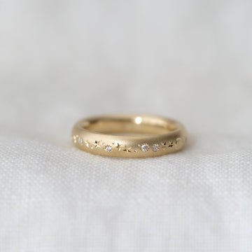 Gold ring with small diamonds on a white fabric background