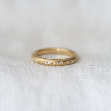 Gold ring with small diamonds on a white fabric background