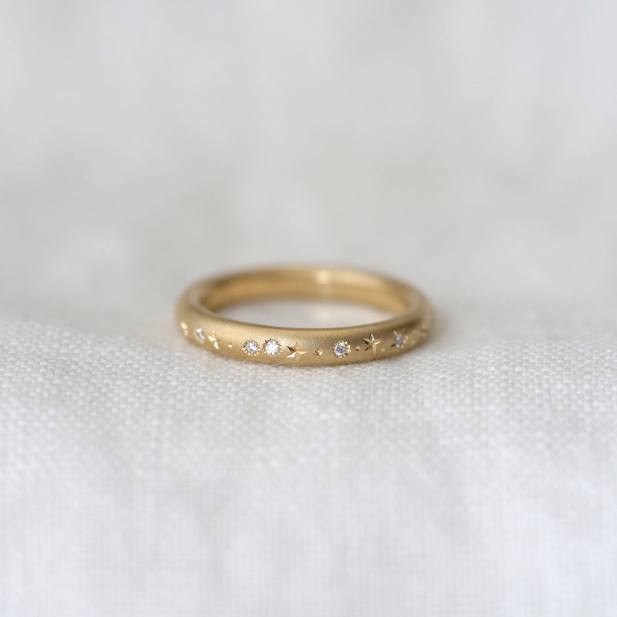 Gold ring with small diamonds on a white fabric background
