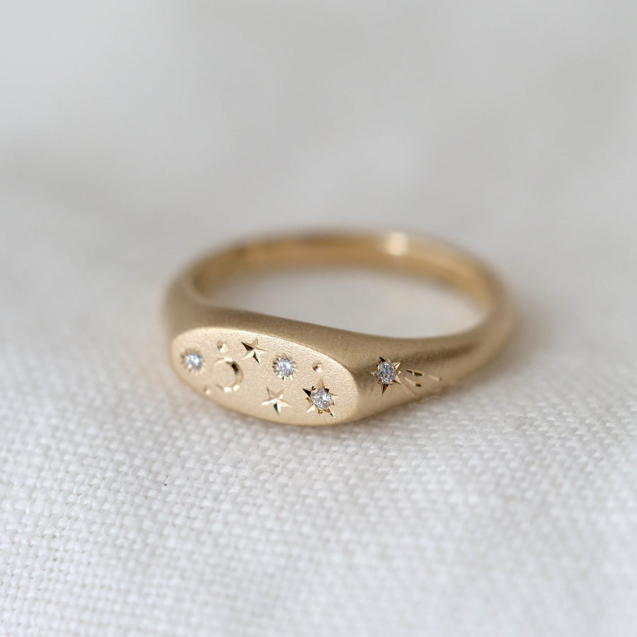Gold ring with embedded diamonds on a white fabric background