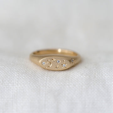Gold ring with embedded stones on a white fabric background