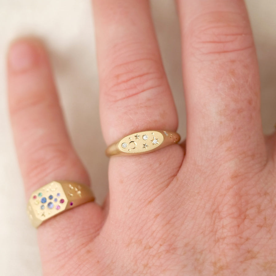 Close-up of a hand wearing two gold rings with gemstones on a light background
