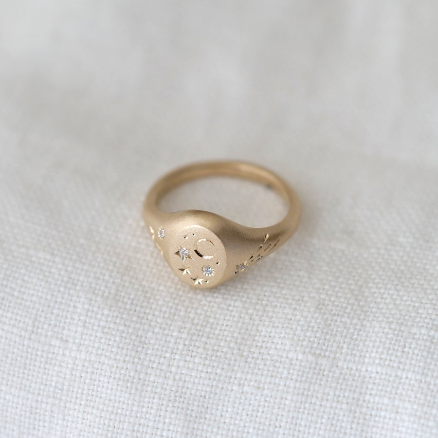 Gold ring with engraved design on a white fabric background