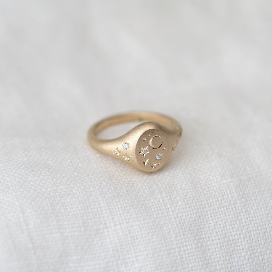 Gold ring with a heart-shaped design on a white fabric background