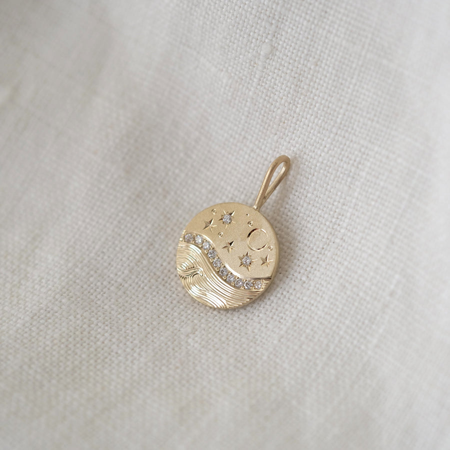 Gold pendant with moon and star design on a light fabric background