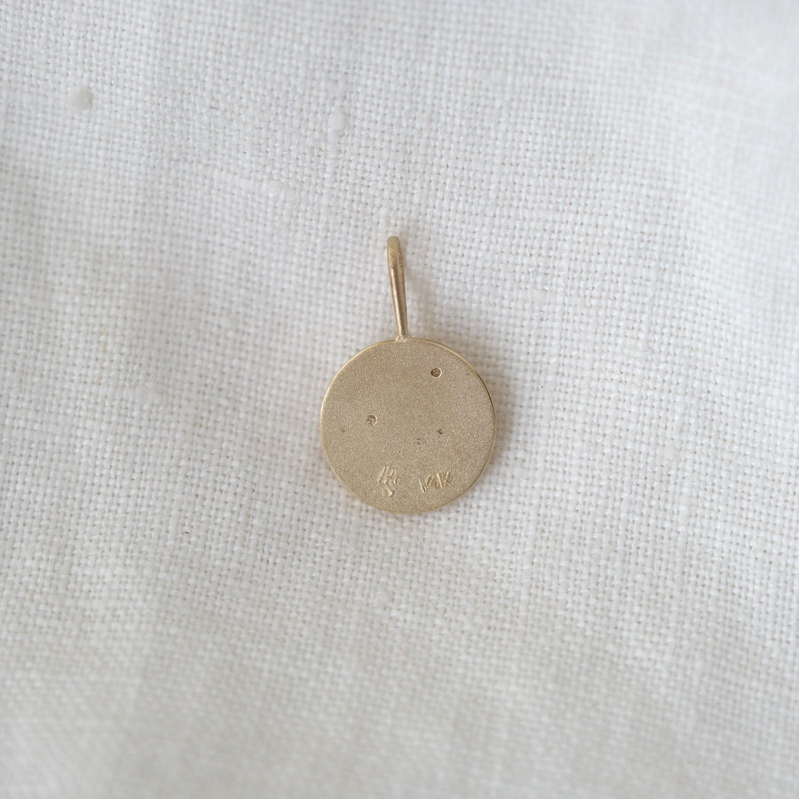 Gold pendant on a white fabric background