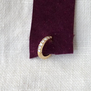 Gold hoop earring on a purple fabric background
