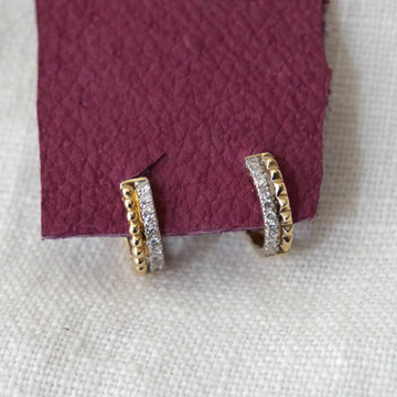 Gold and silver hoop earrings on a textured purple and white background