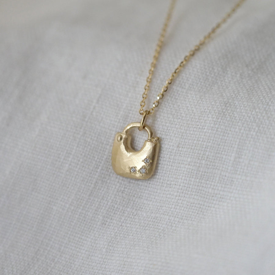 Gold padlock-shaped pendant necklace on a light gray background