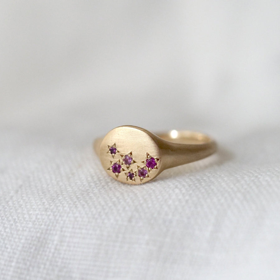 Gold ring with embedded gemstones on a white fabric background