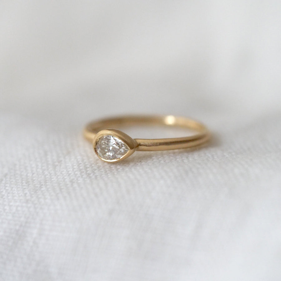 Gold ring with a diamond on a white fabric background