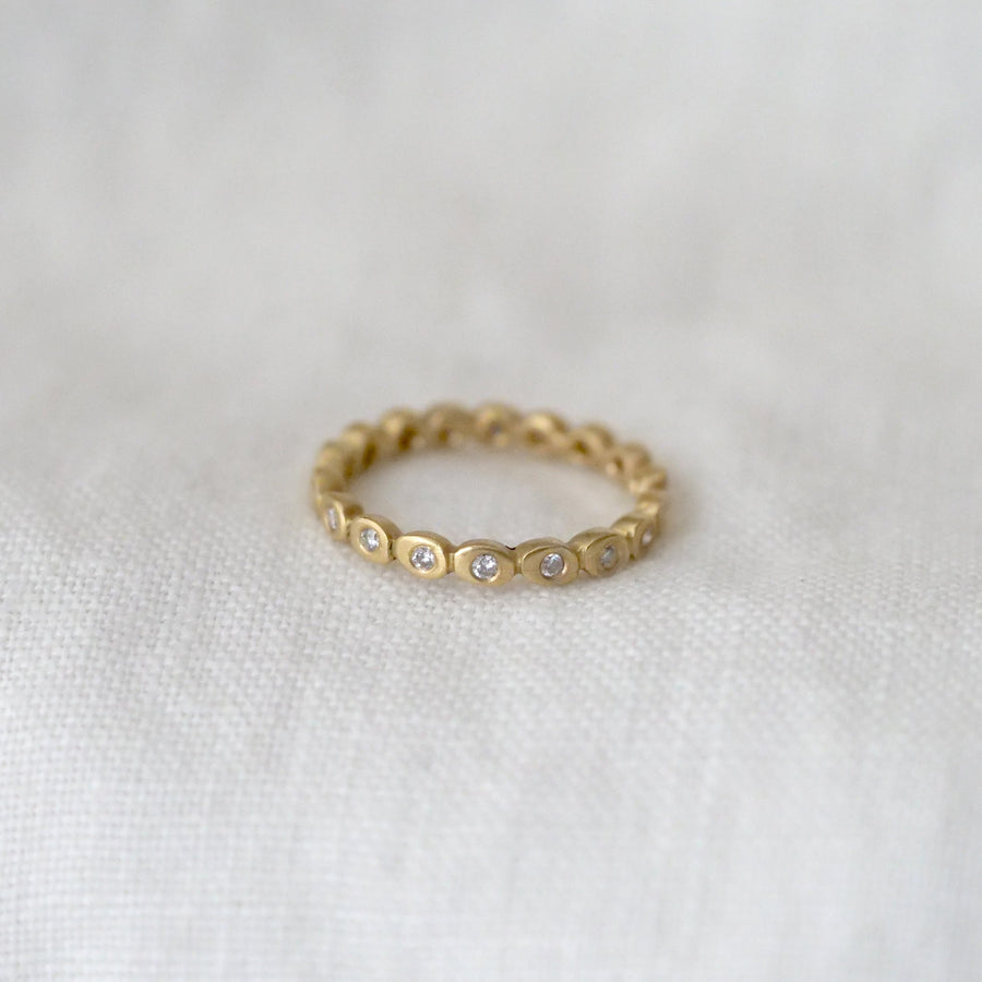 Gold ring with small diamonds on a white fabric background