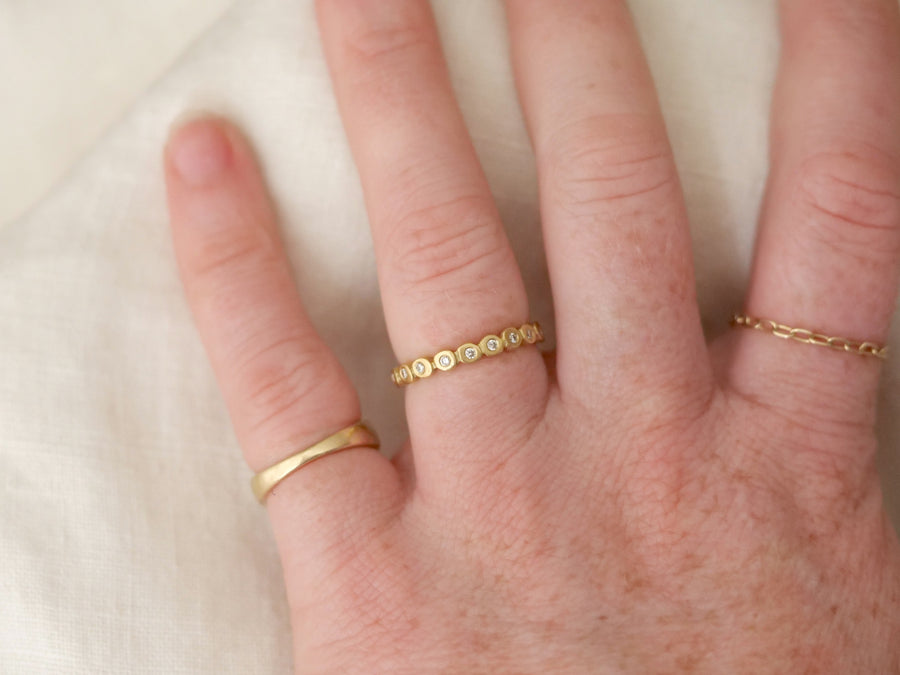 Hand wearing two gold rings on a light background