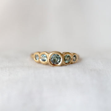 Gold ring with green gemstones on a white background