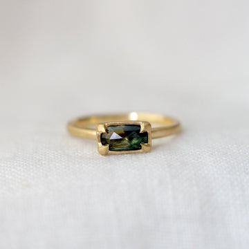 Gold ring with a green gemstone on a white background