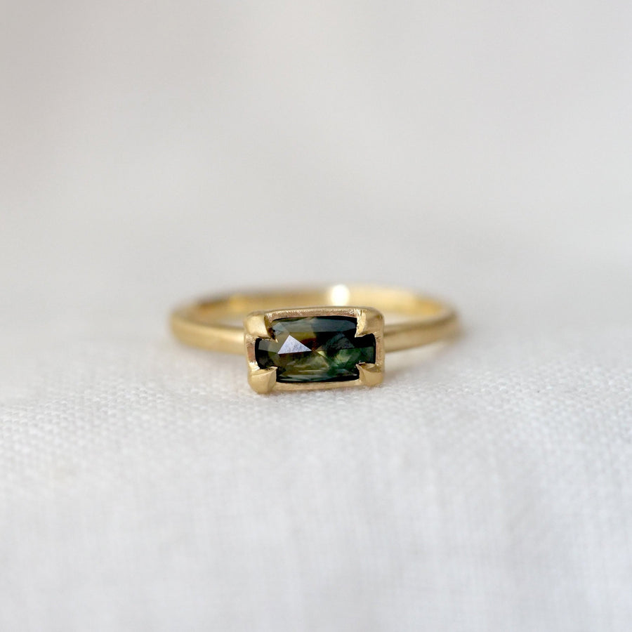 Gold ring with a green gemstone on a white background