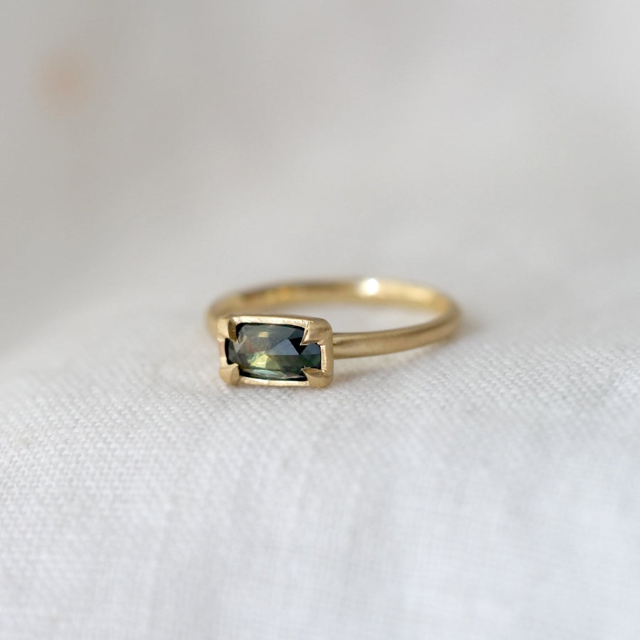 Gold ring with a green gemstone on a white background