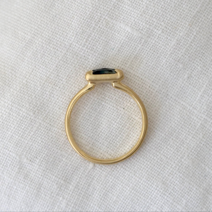 Gold ring with a black gemstone on a white fabric background