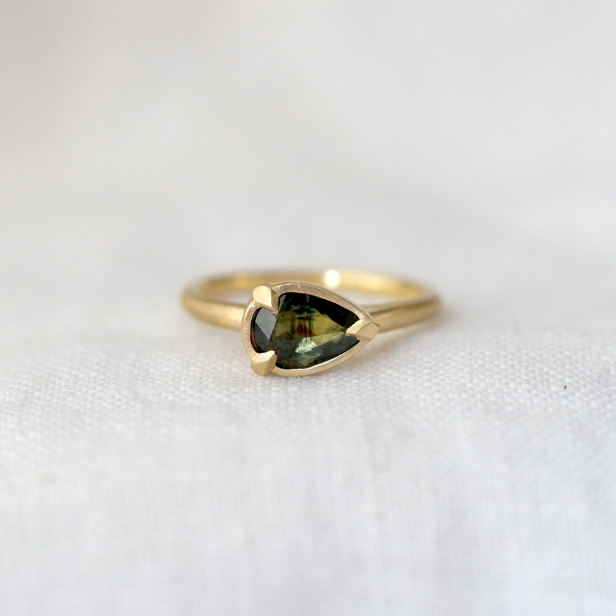 Gold ring with a green gemstone on a white background