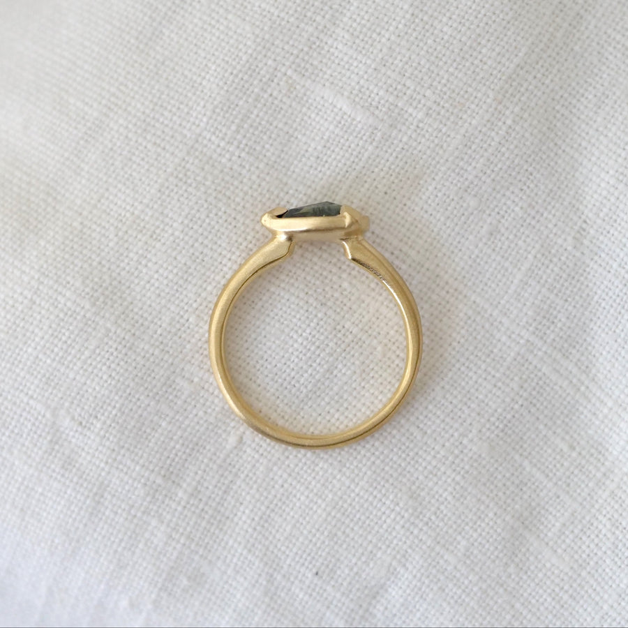 Gold ring with a black gemstone on a white fabric background